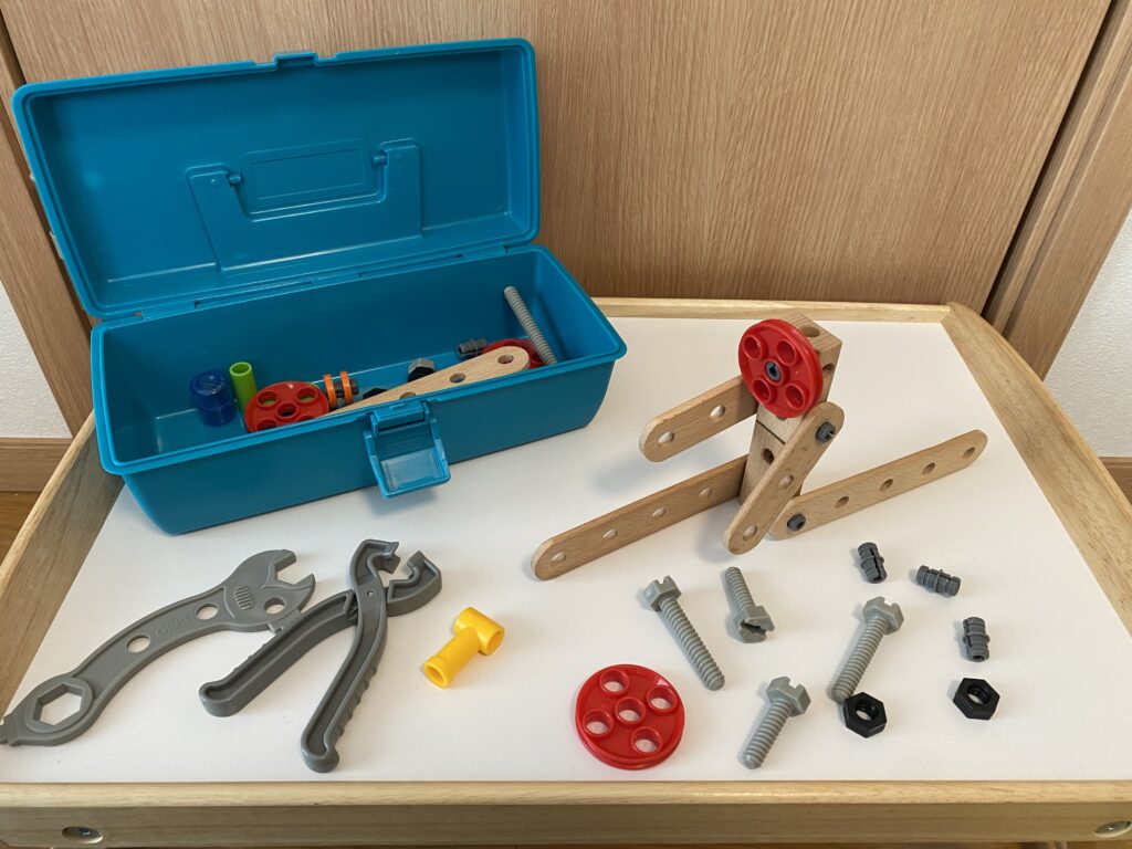 箱から出して、工具セットやねじ、木を組み合わせて作った作品が机の上に並んでいる
