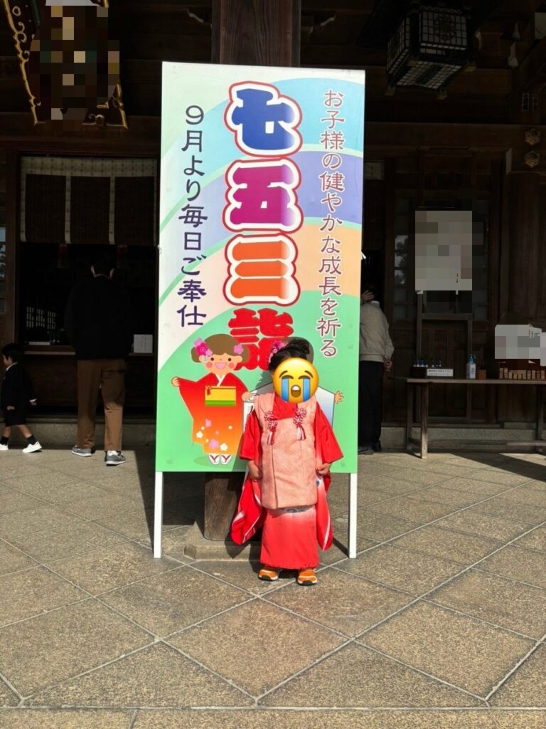 神社にある七五三の看板の前に立つ子ども